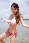 rondborstige aziatische anri sugihara op het strand in een roze bikini