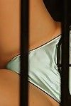 Nikki Nova is locked in a cage wearing a blue corset and panties.